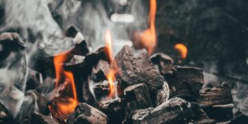 Carvão para churrasco aceso soltando fumaça e chamas
