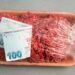 Preço da carne em alta representado por dinheiro sobre bandeja de carne moída