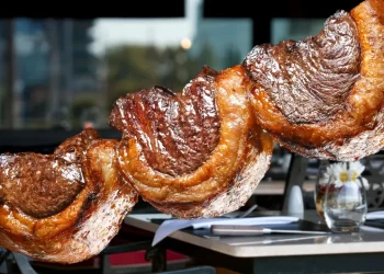 Picanha brasileira assada no espeto, com capa de gordura dourada e suculenta, servida em churrascaria.