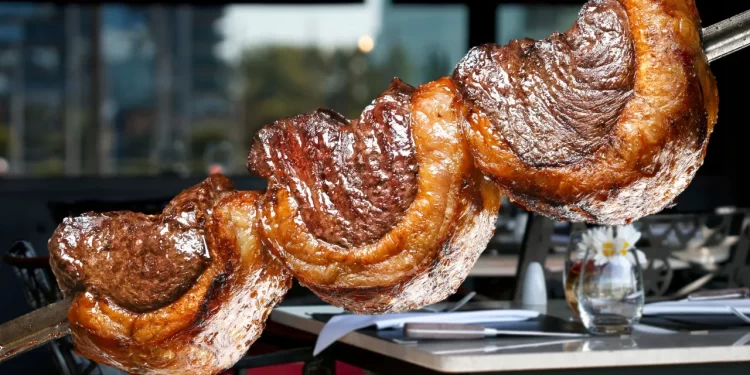 Picanha brasileira assada no espeto, com capa de gordura dourada e suculenta, servida em churrascaria.